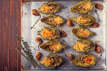 Artichokes baked with cheese, garlic and thyme on a baking sheet, top view.